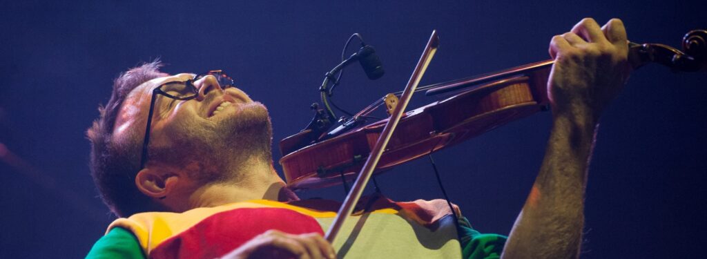 Man in brightly coloured top playing the violin