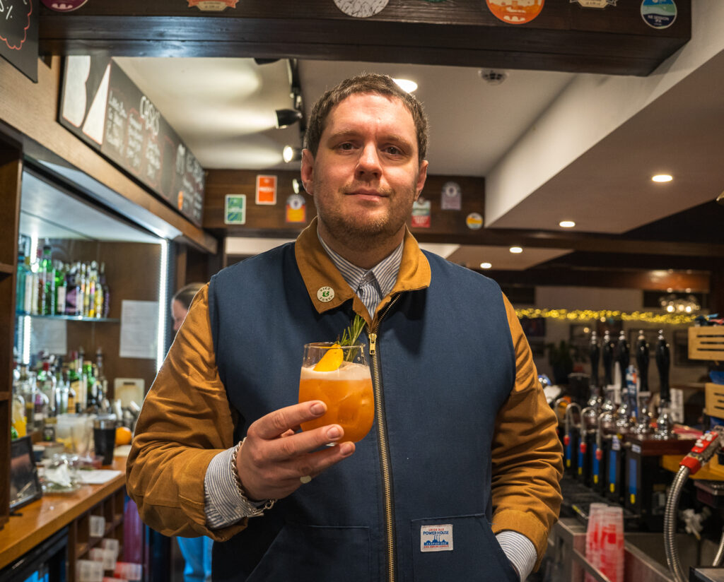 Paul holding a cocktail in by the bar